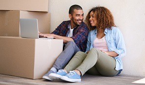 Couple sitting in new house on laptop