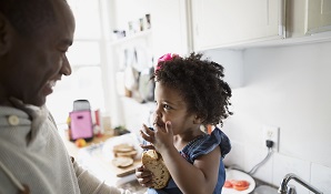 Father and daughter in kitchen eating a cookie