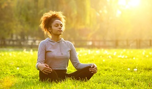 woman sitting on grass in the sun looking relaxed