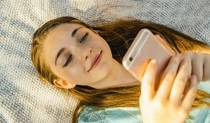 Young girl laying down playing on cellphone