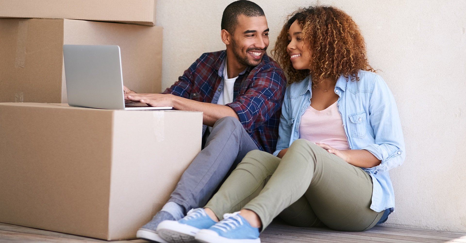 Couple sitting in new house on laptop