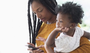 Mother looking at cellphone and holding child