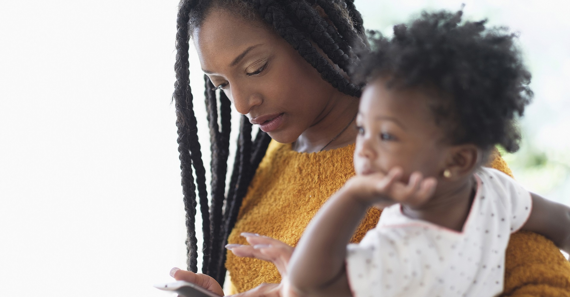 Mother looking at cellphone and holding child