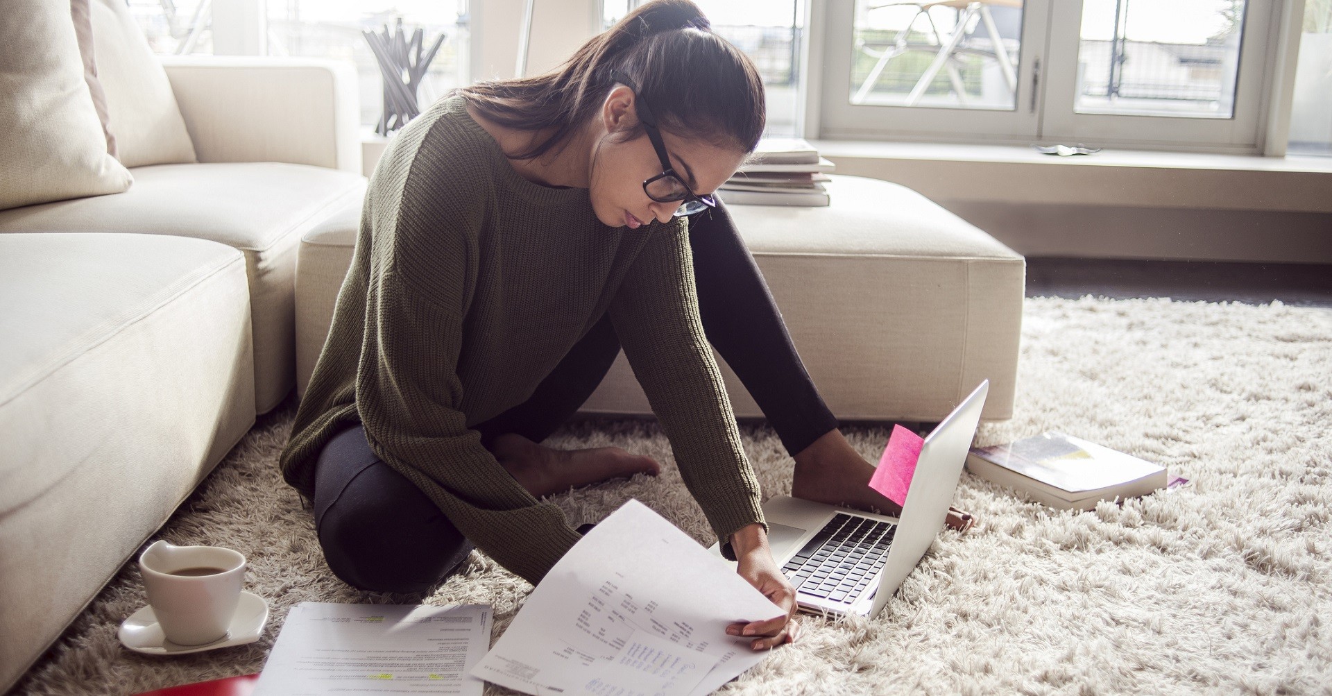 Woman sitting on carpet working out budget