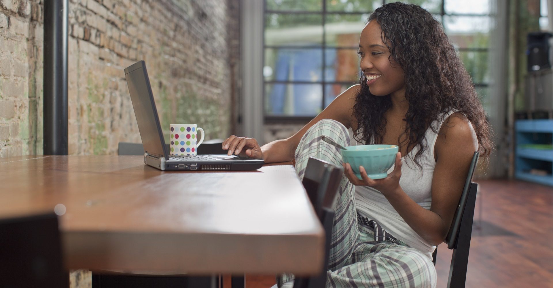 Woman sitting at desk eating breakfast