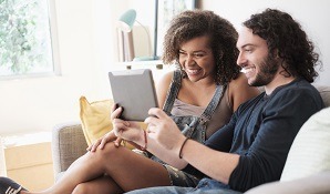 Couple sitting on couch looking at tablet
