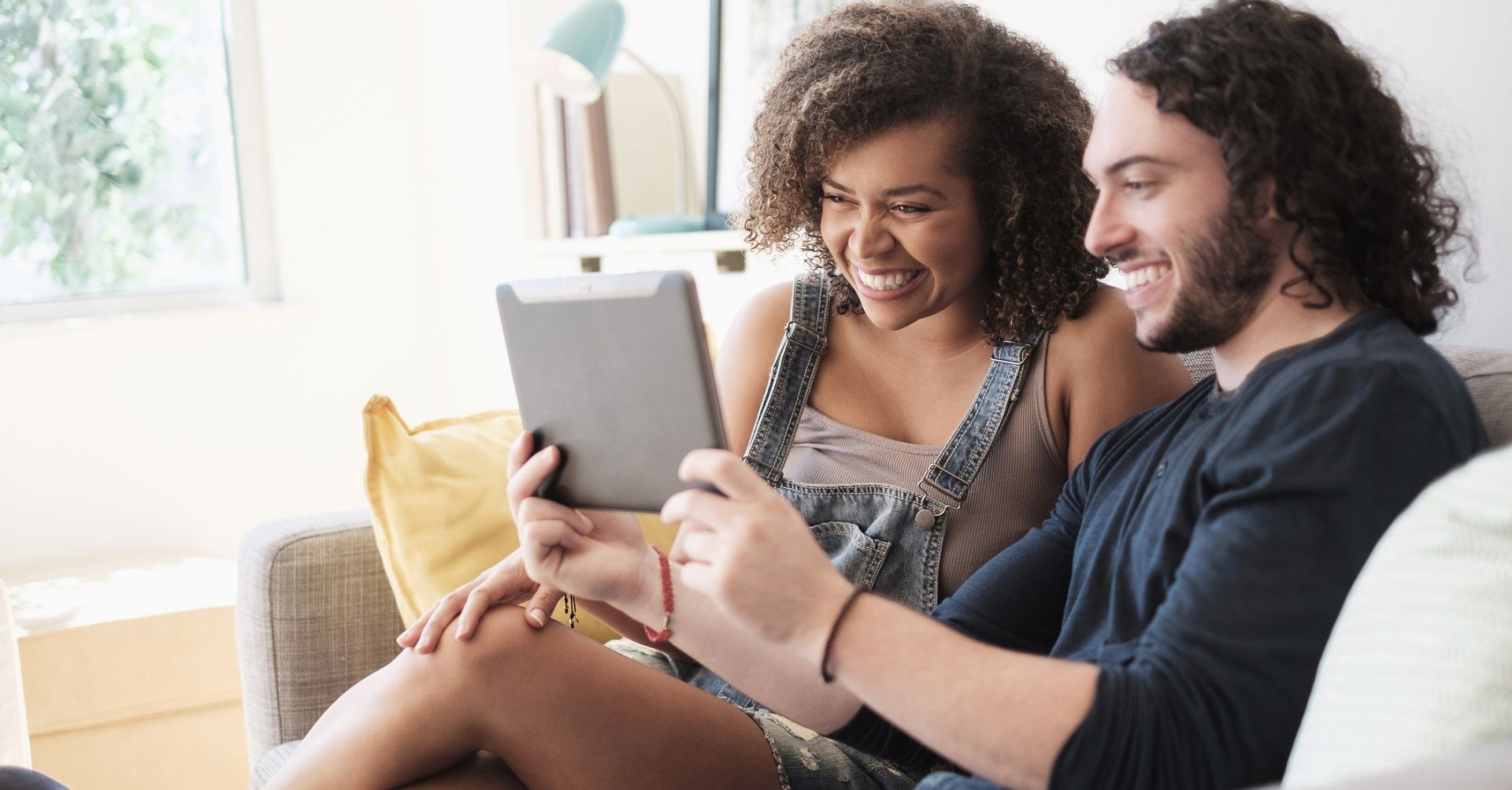 Couple sitting on couch looking at tablet