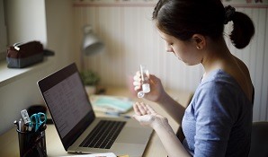 Girl sitting at desk using hand sanitizer