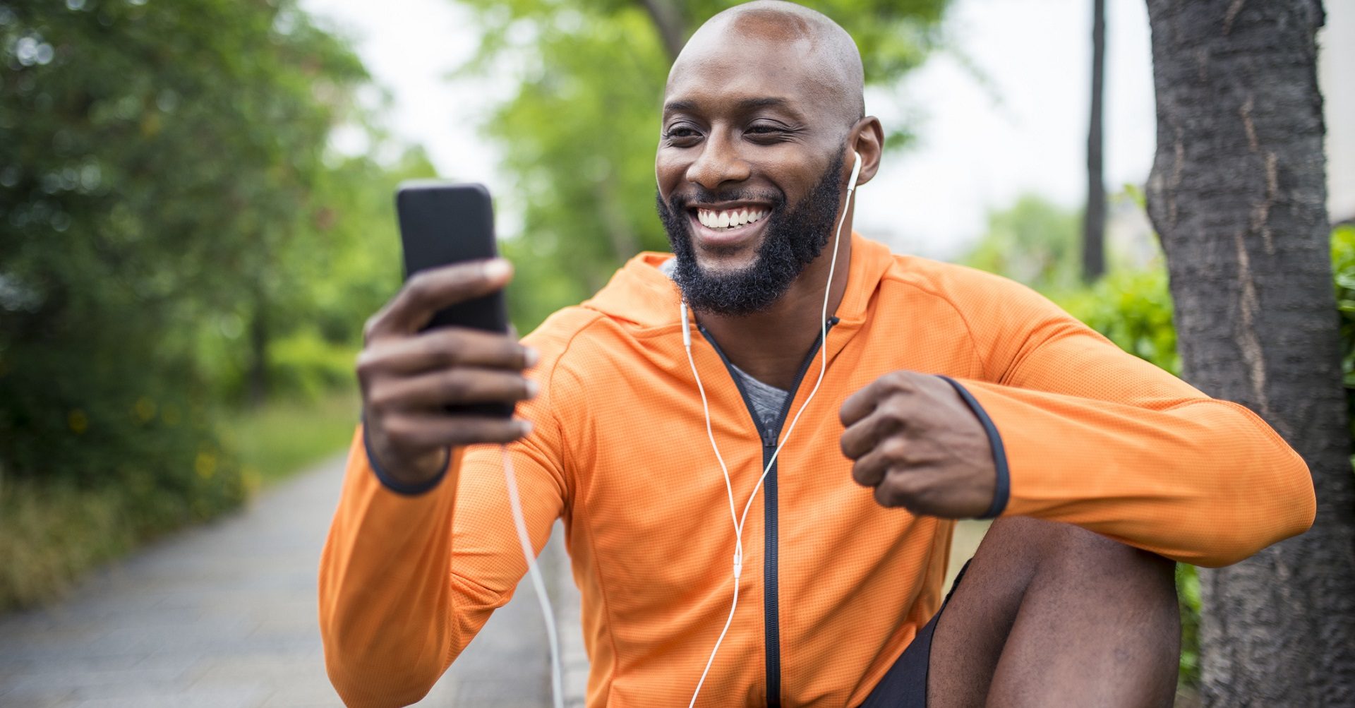 Man sitting on bench in workout clothes on cellphone