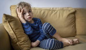 Little boy sitting on the couch looking sad