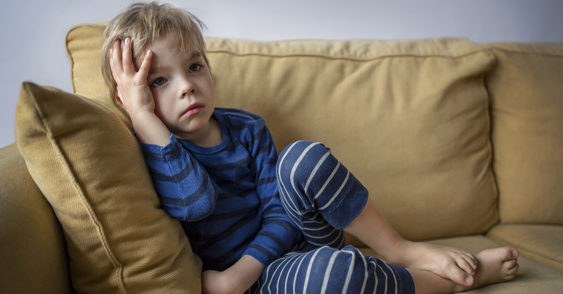 Little boy sitting on the couch looking sad