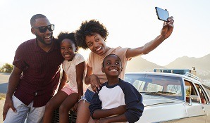 Family taking selfie in front of car