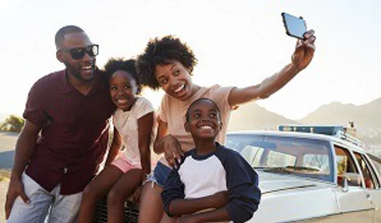 Family taking selfie in front of car