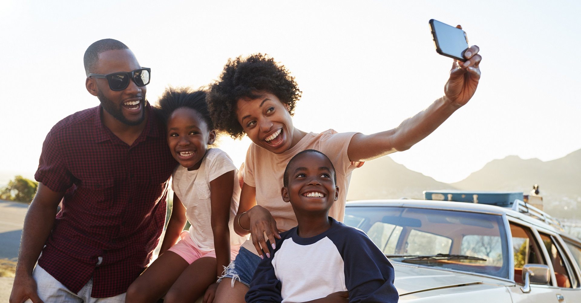 Family taking selfie in front of car