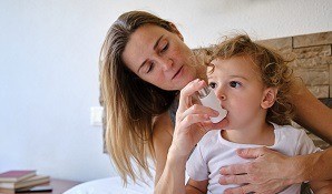 Mother assisting child with asthma inhaler