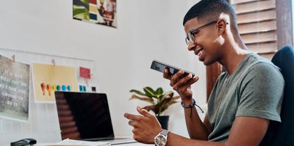 Man sitting at computer on cellphone