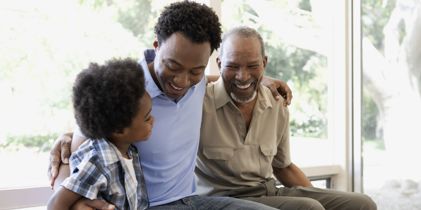 Grandfather, father and son sitting on bed
