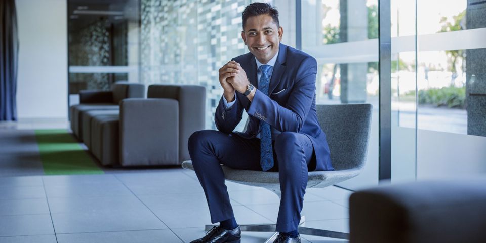 Man in a blue suit sitting on a chair and smiling
