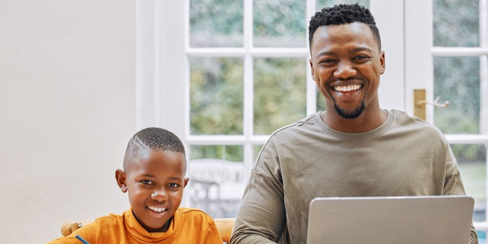 father and son at laptop smiling