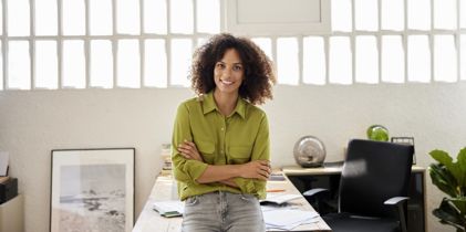 Woman leaning on desk with arms folded