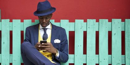 Man sitting in front of fence looking at cellphone