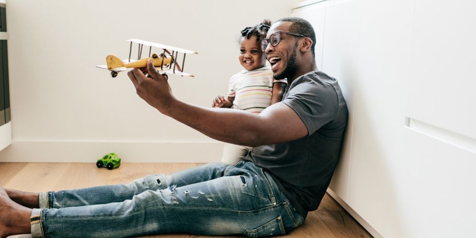 Father holding daughter with a wooden plane in his hand