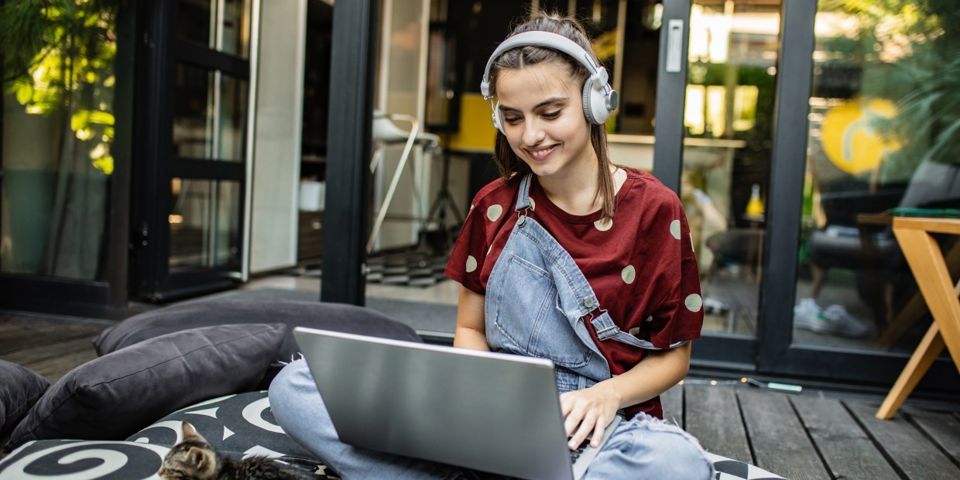 Teenager with headphones looking at laptop