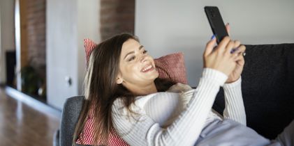 woman lying on couch using phone