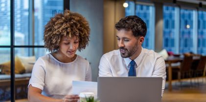 two people discussing at table with laptop