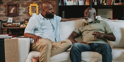 Adult man talking to father on couch