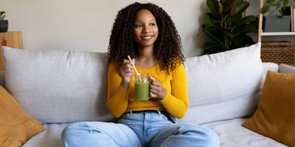 woman on couch drinking smoothie