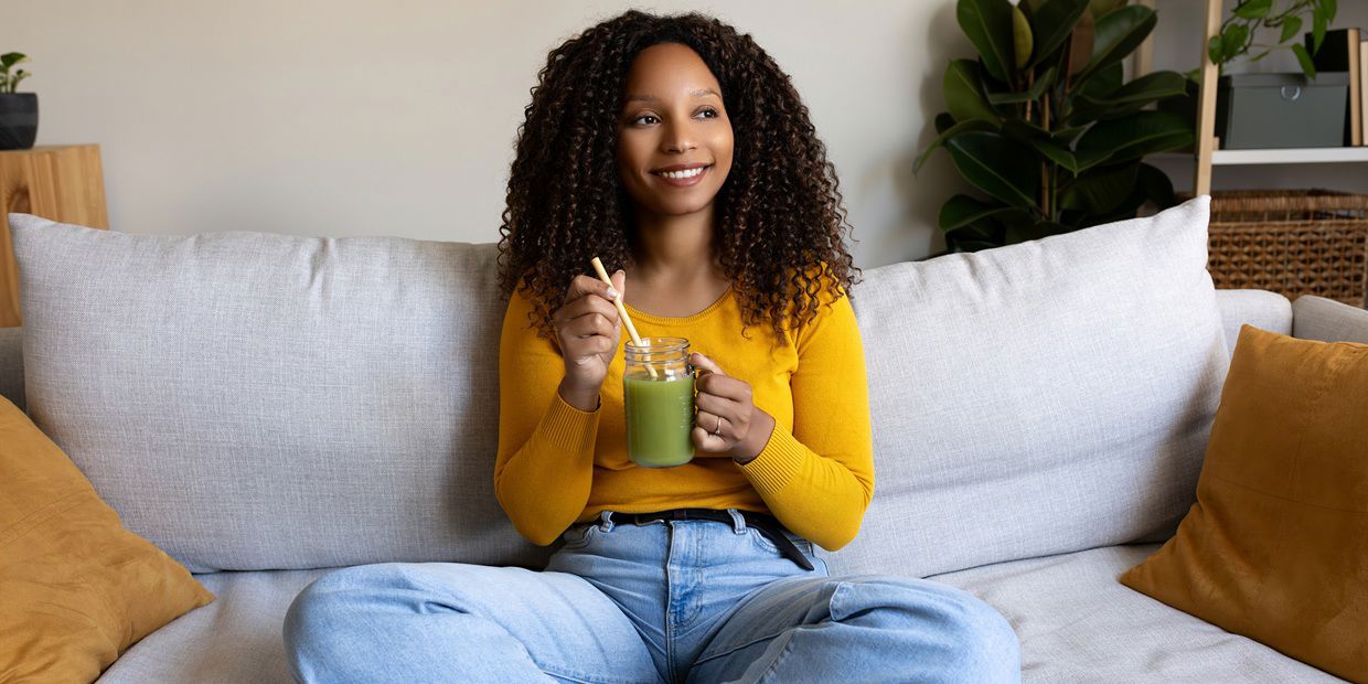 woman on couch drinking smoothie