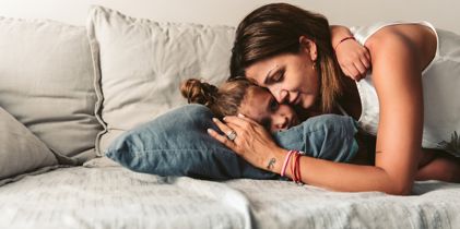 mother hugging daughter on couch