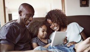 happy family sitting on couch looking at tablet