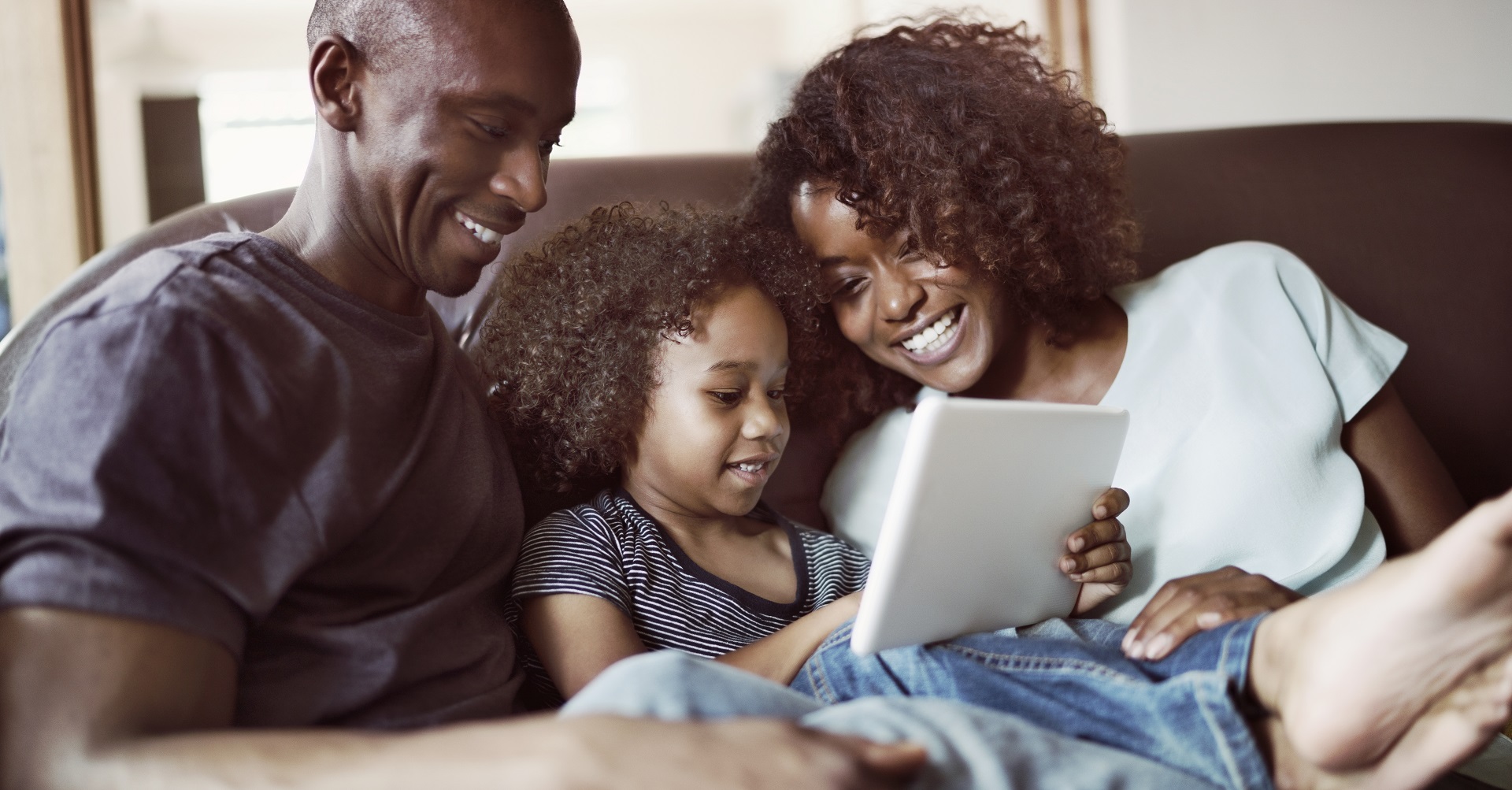 happy family sitting on couch looking at tablet