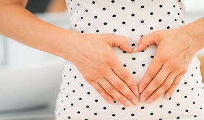 Woman with hands in heart shape in front of stomach