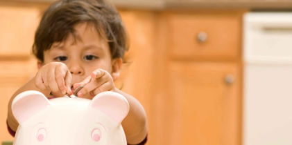 little girl putting coins into a piggy bank