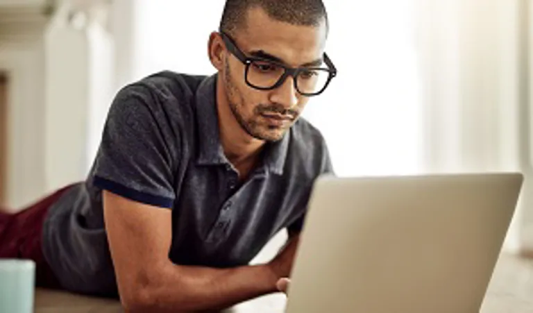 man lying on stomach looking at laptop