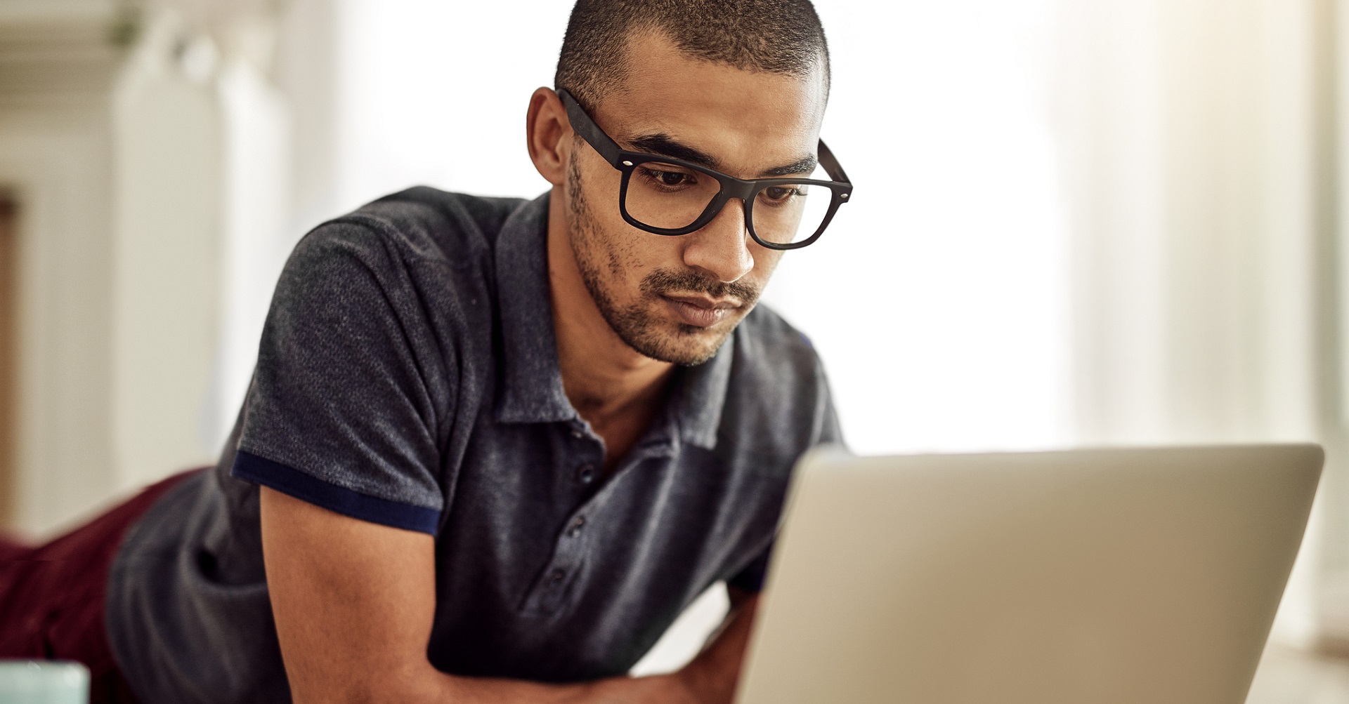 man lying on stomach looking at laptop