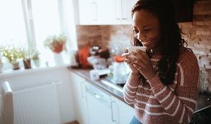 woman standing in kitchen drinking coffee