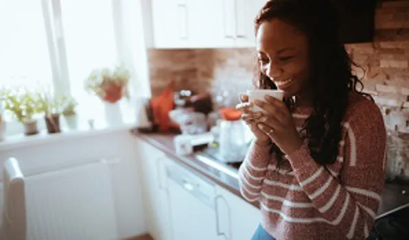 woman standing in kitchen drinking coffee