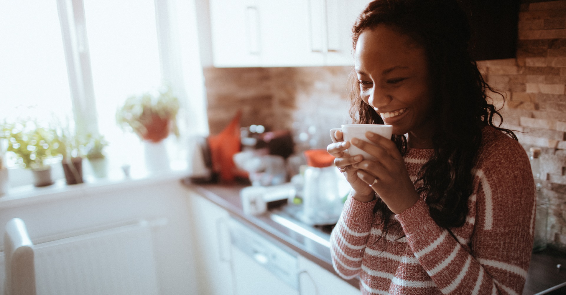 woman standing in kitchen drinking coffee