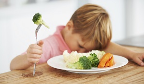 child sitting in front of plate of veggies