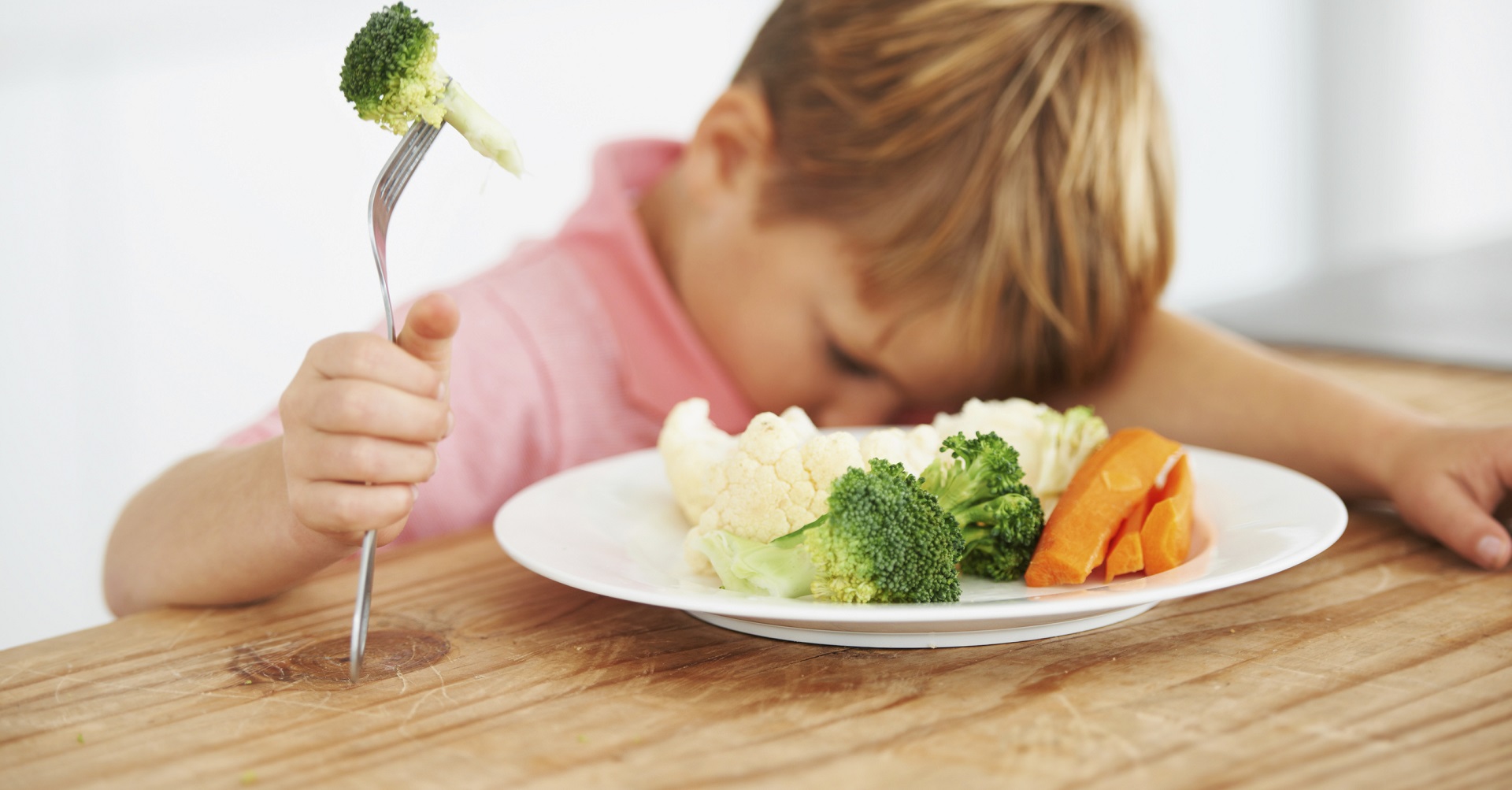 child sitting in front of plate of veggies