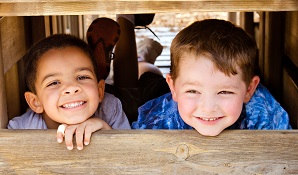 young boys lying behind piece of wood