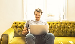 Man sitting on a couch with an open laptop