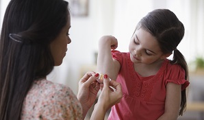 mom putting plaster on daughters elbow