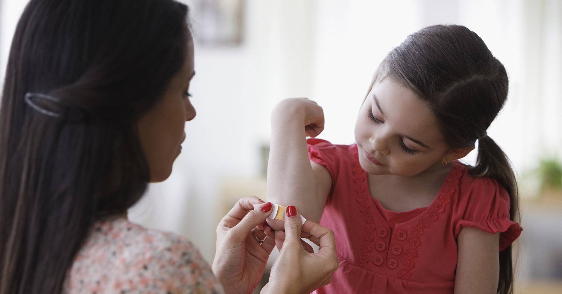 mom putting plaster on daughters elbow