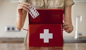 woman putting medicine into first aid kit