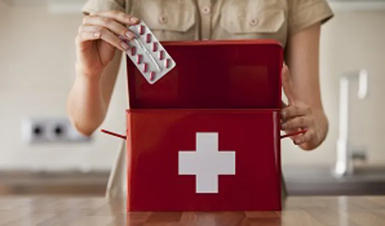 woman putting medicine into first aid kit